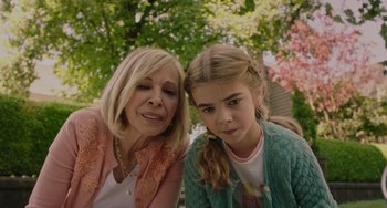 Movie still from “Flora & Ulysses” (2021), directed by Lena Khan – A woman sitting next to a young girl in front of trees; Close Up shot, High angle