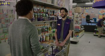 Movie still from “Flora & Ulysses” (2021), directed by Lena Khan – A man talking to a customer in a grocery store; Medium shot, Over the shoulder angle