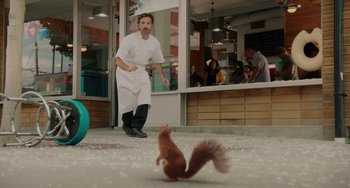 Movie still from “Flora & Ulysses” (2021), directed by Lena Khan – A man standing in front of a squirrel on the ground; Wide shot, Low angle