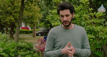 Movie still from “Flora & Ulysses” (2021), directed by Lena Khan – A man in a green shirt standing next to some bushes; Medium shot, Over the shoulder angle
