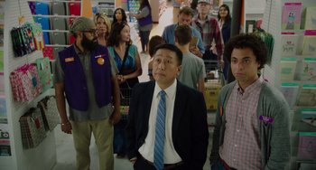 Movie still from “Flora & Ulysses” (2021), directed by Lena Khan – A group of people standing around each other in a room; Medium shot, Over the shoulder angle