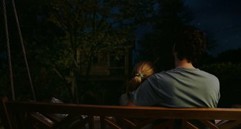 Movie still from “Flora & Ulysses” (2021), directed by Lena Khan – A man and a woman sitting on top of a wooden bench; Medium shot, High angle