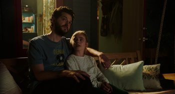 Movie still from “Flora & Ulysses” (2021), directed by Lena Khan – A man and a woman sitting on a couch; Medium shot, Low angle