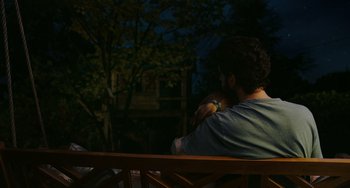 Movie still from “Flora & Ulysses” (2021), directed by Lena Khan – A man sitting on top of a wooden park bench; Medium shot, Over the shoulder angle