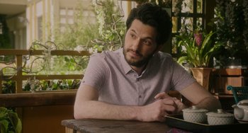 Movie still from “Flora & Ulysses” (2021), directed by Lena Khan – A man sitting at a table with a book in front of him; Medium shot, Over the shoulder angle