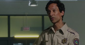 Movie still from “Flora & Ulysses” (2021), directed by Lena Khan – A man in a police uniform standing next to an exit sign; Close Up shot, Low angle