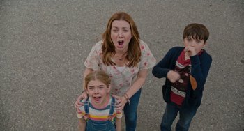 Movie still from “Flora & Ulysses” (2021), directed by Lena Khan – A woman standing next to two children on a street; Medium shot, Low angle