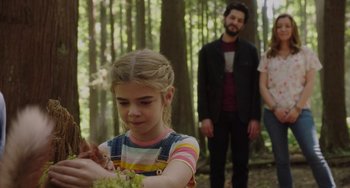 Movie still from “Flora & Ulysses” (2021), directed by Lena Khan – A young girl holding a bunch of flowers in a forest; Medium shot, Over the shoulder angle