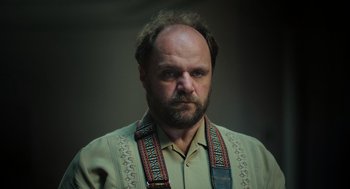 Movie still from “Flux Gourmet” (2022), directed by Peter Strickland – A man with a beard wearing a neck tie; Close Up shot, Low angle