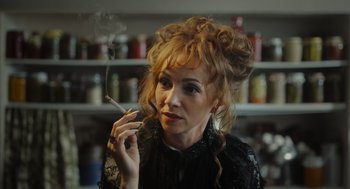 Movie still from “Flux Gourmet” (2022), directed by Peter Strickland – A woman smoking a cigarette while wearing a black dress; Close Up shot, Low angle