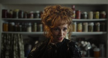 Movie still from “Flux Gourmet” (2022), directed by Peter Strickland – A person wearing a black dress; Close Up shot, Over the shoulder angle