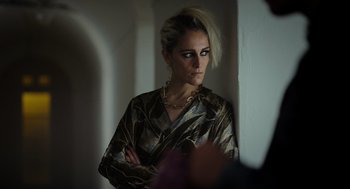 Movie still from “Flux Gourmet” (2022), directed by Peter Strickland – A woman in a gold and black dress looking at a mirror; Close Up shot, Low angle