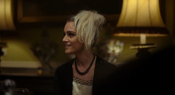 Movie still from “Flux Gourmet” (2022), directed by Peter Strickland – A woman wearing a black necklace and a white jacket; Close Up shot, Over the shoulder angle