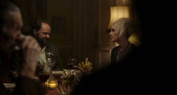Movie still from “Flux Gourmet” (2022), directed by Peter Strickland – A man and a woman sitting at a dinner table; Medium shot, Over the shoulder angle