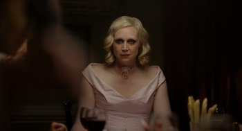 Movie still from “Flux Gourmet” (2022), directed by Peter Strickland – A woman sitting at a table with a glass of red wine; Close Up shot, Over the shoulder angle