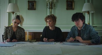 Movie still from “Flux Gourmet” (2022), directed by Peter Strickland – A group of people sitting at a table with papers; Medium shot, Low angle