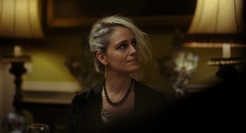 Movie still from “Flux Gourmet” (2022), directed by Peter Strickland – A woman wearing a black jacket and a black necklace; Close Up shot, Low angle