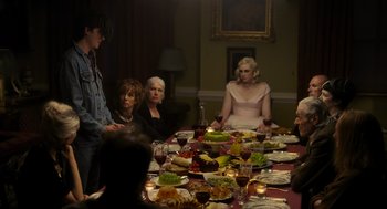 Movie still from “Flux Gourmet” (2022), directed by Peter Strickland – A group of people sitting around a table with food; Wide shot, Over the shoulder angle