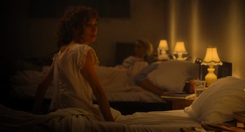 Movie still from “Flux Gourmet” (2022), directed by Peter Strickland – A woman sitting on a bed in front of a man in bed; Medium shot, Over the shoulder angle