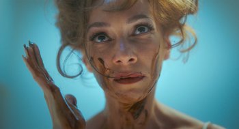 Movie still from “Flux Gourmet” (2022), directed by Peter Strickland – A person with makeup on their face; Close Up shot, Overhead angle