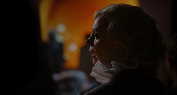 Movie still from “Flux Gourmet” (2022), directed by Peter Strickland – A woman with blonde hair looking to her left; Close Up shot, Over the shoulder angle
