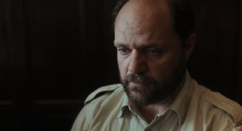 Movie still from “Flux Gourmet” (2022), directed by Peter Strickland – A person with a beard; Close Up shot, Low angle