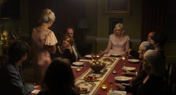 Movie still from “Flux Gourmet” (2022), directed by Peter Strickland – A group of people sitting around a dinner table; Medium shot, Over the shoulder angle