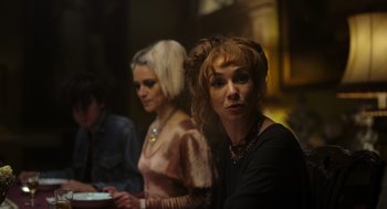 Movie still from “Flux Gourmet” (2022), directed by Peter Strickland – Two women sitting in front of a man in a room; Medium shot, Over the shoulder angle