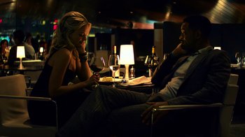 Movie still from “Focus” (2015), directed by John Requa – A man and a woman sitting at a dinner table; Medium shot, Over the shoulder angle