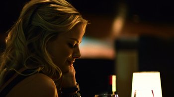 Movie still from “Focus” (2015), directed by John Requa – A woman sitting at a table with a glass of red wine; Close Up shot, Over the shoulder angle