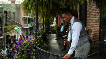 Movie still from “Focus” (2015), directed by John Requa – A man standing on a balcony holding a pole; Medium shot, Over the shoulder angle