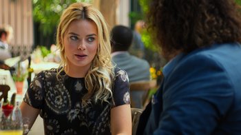 Movie still from “Focus” (2015), directed by John Requa – A woman sitting at an outdoor table talking to another woman; Close Up shot, Over the shoulder angle