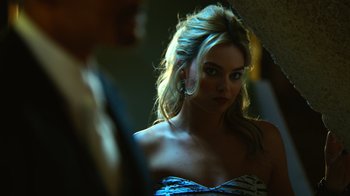 Movie still from “Focus” (2015), directed by John Requa – A beautiful blonde woman in a strapless dress; Close Up shot, Over the shoulder angle