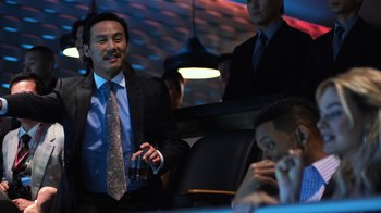 Movie still from “Focus” (2015), directed by John Requa – A group of men sitting around a table; Medium shot, Over the shoulder angle