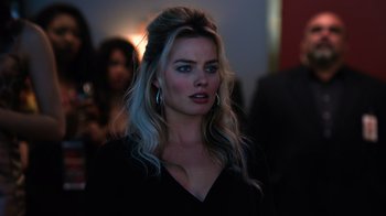 Movie still from “Focus” (2015), directed by John Requa – A woman with blonde hair wearing a black top; Close Up shot, Over the shoulder angle