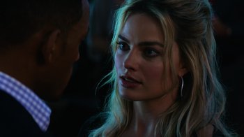 Movie still from “Focus” (2015), directed by John Requa – A woman with long blonde hair looking at the camera; Close Up shot, Over the shoulder angle