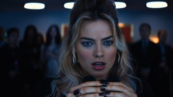 Movie still from “Focus” (2015), directed by John Requa – A beautiful woman with long blonde hair and black nail polish; Close Up shot, Over the shoulder angle