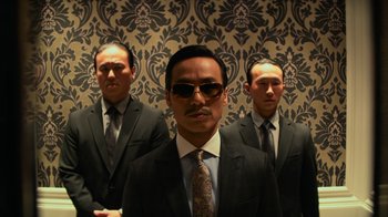 Movie still from “Focus” (2015), directed by John Requa – A group of men in suits and ties standing in front of a wall; Medium shot, Low angle