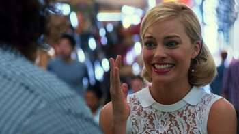 Movie still from “Focus” (2015), directed by John Requa – A woman smiling and waving at the camera; Close Up shot, Over the shoulder angle