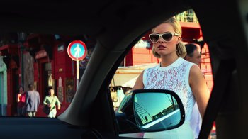 Movie still from “Focus” (2015), directed by John Requa – A woman in a white dress is in the side view mirror of a car; Medium shot, Low angle