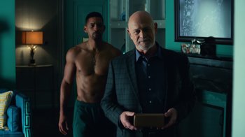 Movie still from “Focus” (2015), directed by John Requa – A man standing next to another man holding a box; Medium shot, Over the shoulder angle