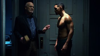 Movie still from “Focus” (2015), directed by John Requa – A man standing next to another man in front of a door; Medium shot, Over the shoulder angle