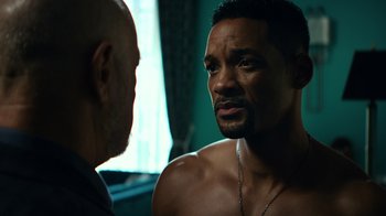 Movie still from “Focus” (2015), directed by John Requa – A man with a shaved head talking to another man in front of a window; Close Up shot, Over the shoulder angle