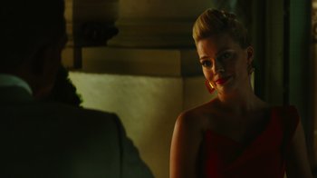 Movie still from “Focus” (2015), directed by John Requa – A woman in a red dress smiling for the camera; Close Up shot, Over the shoulder angle