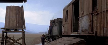 Movie still from “For a Few Dollars More” (1965), directed by Sergio Leone – Two men standing on the side of a train car; Extreme Wide shot, Low angle