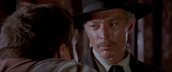 Movie still from “For a Few Dollars More” (1965), directed by Sergio Leone – A person wearing a suit and a hat; Close Up shot, Over the shoulder angle