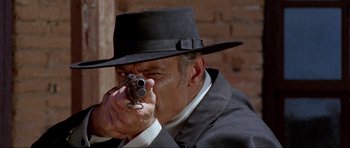 Movie still from “For a Few Dollars More” (1965), directed by Sergio Leone – A man in a black hat is holding a gun; Close Up shot, Low angle