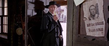 Movie still from “For a Few Dollars More” (1965), directed by Sergio Leone – A man wearing a hat and holding an umbrella; Medium shot, Low angle
