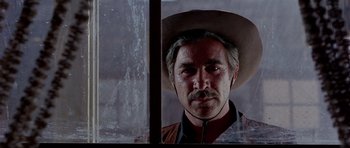 Movie still from “For a Few Dollars More” (1965), directed by Sergio Leone – A man with a cowboy hat looking out of a window; Close Up shot, Low angle
