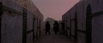 Movie still from “For a Few Dollars More” (1965), directed by Sergio Leone – Two men are standing in an alley way; Wide shot, Low angle